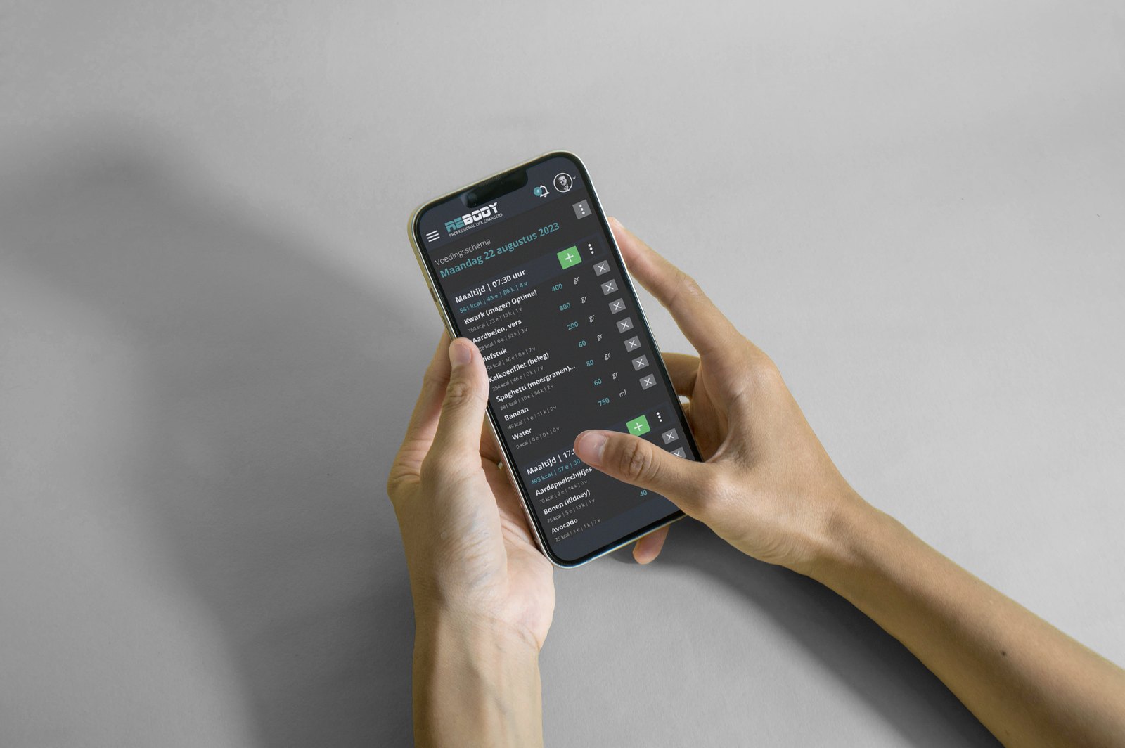 Handen houden een telefoon vast met het Rebody-voedingsschema in de app